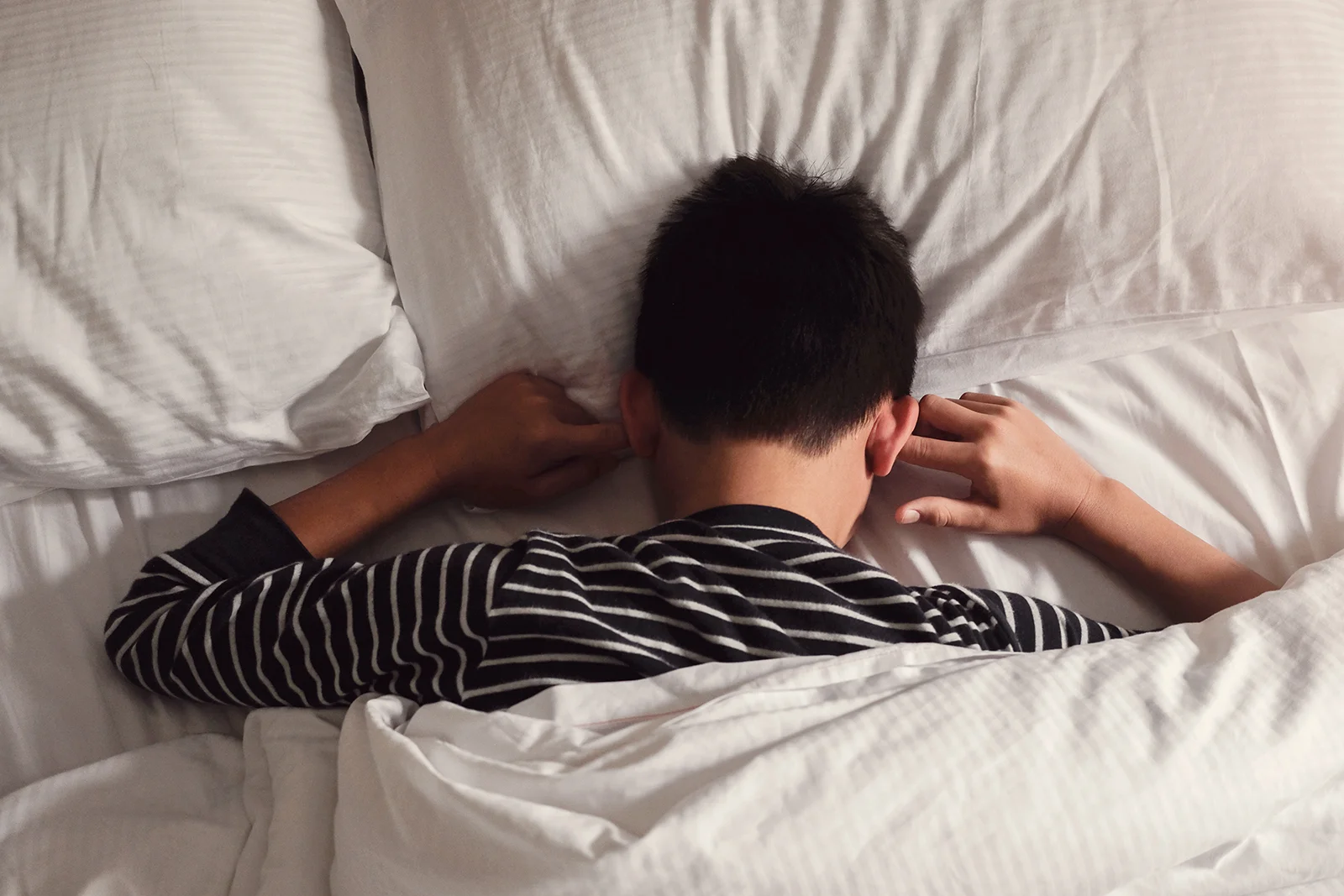 Preteen tween boy covering ears with his fingers in bed