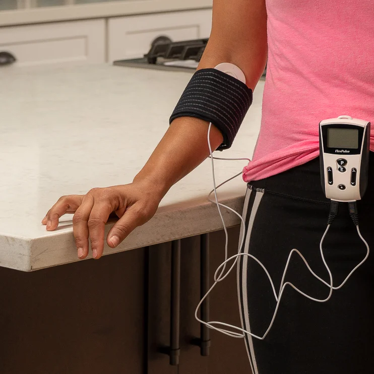 PEMF FlexPulse device strapped to pant leg of a woman while treatment cables are strapped to her elbow