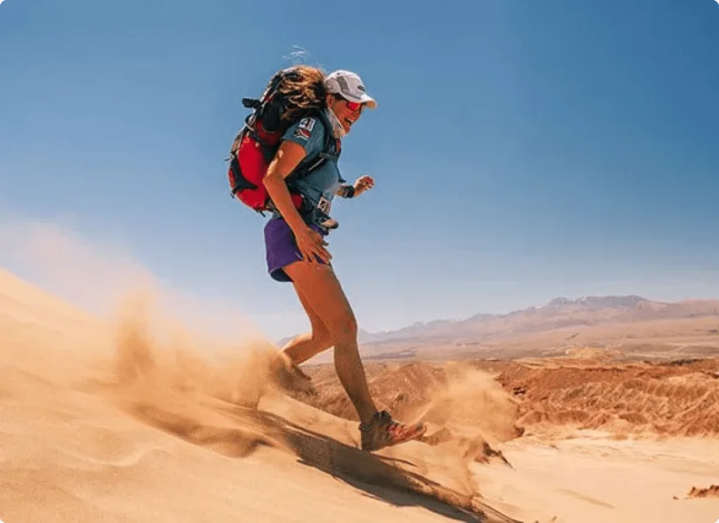 Woman runs down sand hill in the middle of a desert