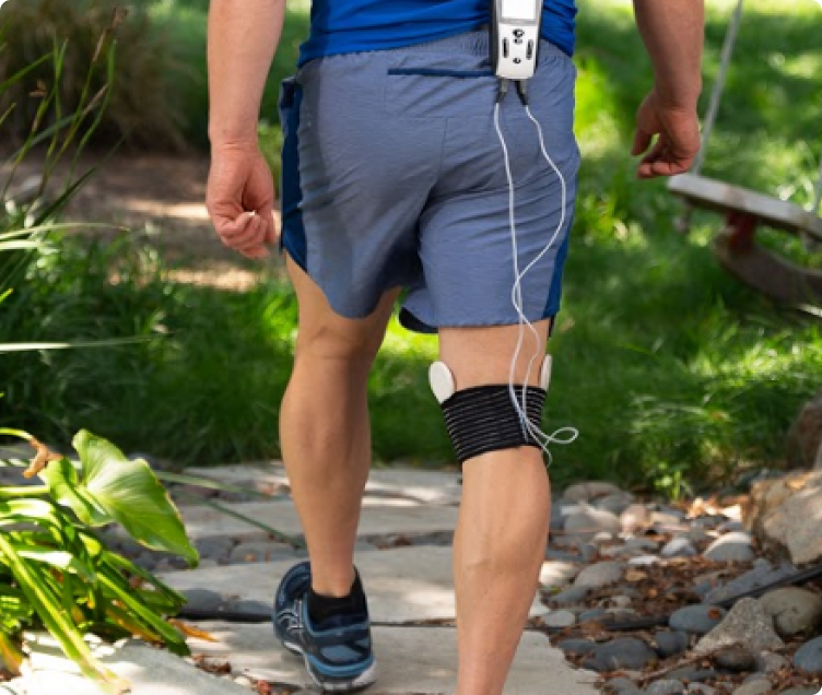 Man walking outdoors with a coil pad strapped to his knee