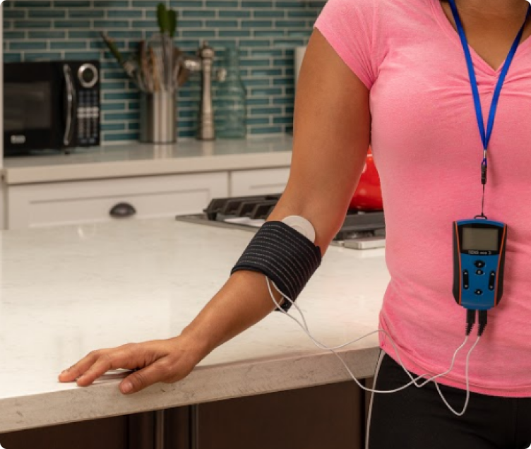 Woman wearing the FlexPulse on a lanyard, a coil pad strapped to her upper arm