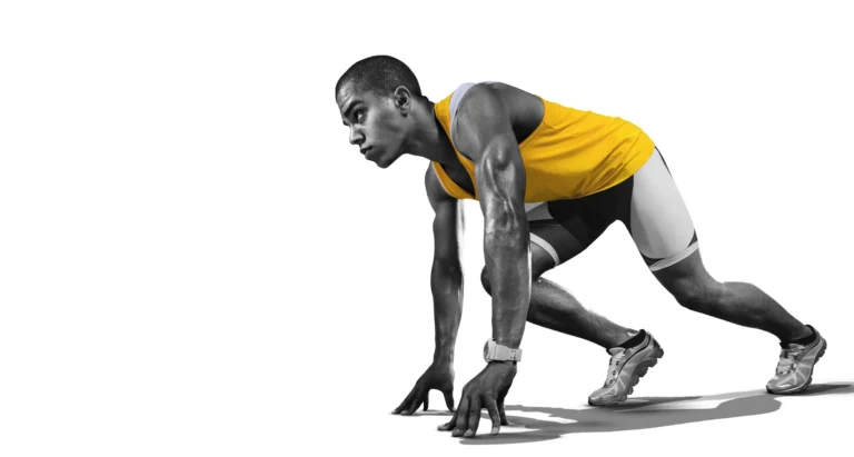 Male runner bent down as though he is waiting for the start of a race and at the startline