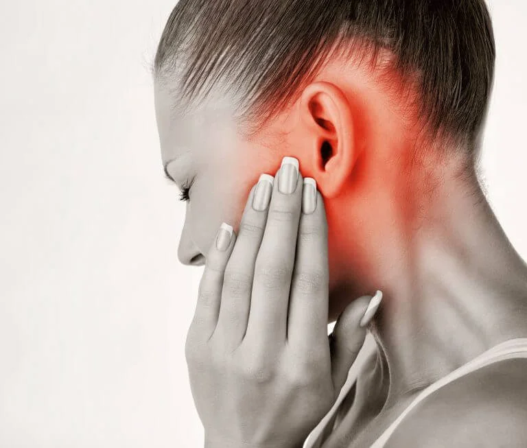 Woman holding jaw in pain due to Tinnitus